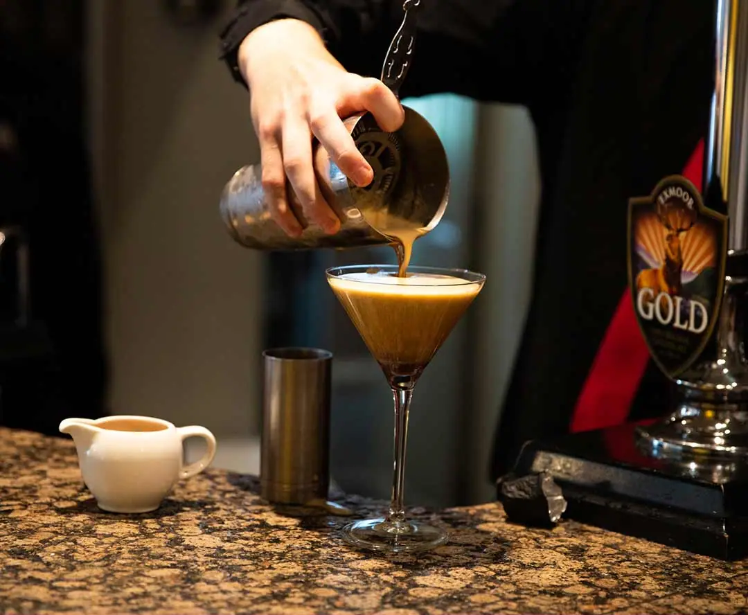 A cocktail being poured at the bar