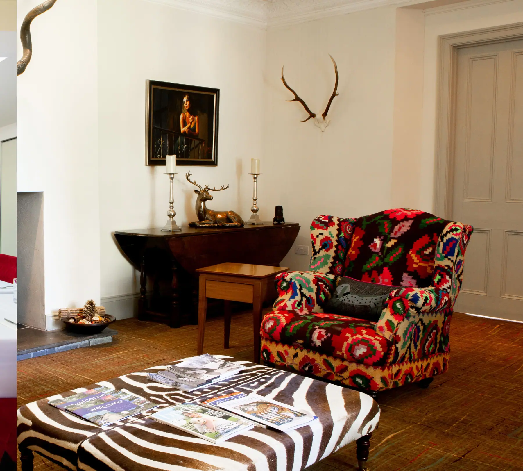A sitting room with antlers above the fireplace and a patterned armchair